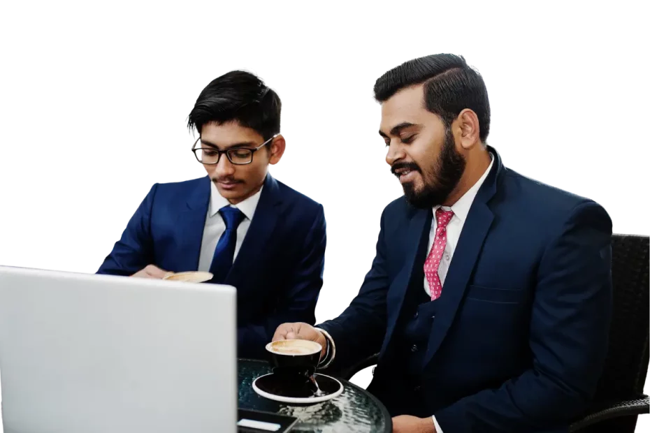 Two business professionals in suits sit at a glass table with a laptop, each holding a cup of coffee as they look at the screen.